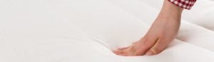 Picture-of-a-hand-pressing-on-a-mattress-to-test-the-firmness