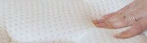 Hand pushing a memory foam mattress.