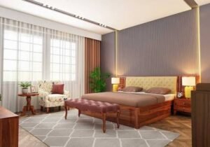 Modern bedroom featuring a wooden platform bed with a tufted upholstered headboard, warm bedside lighting, a cushioned bench, large windows with sheer curtains, and a neutral colour palette.