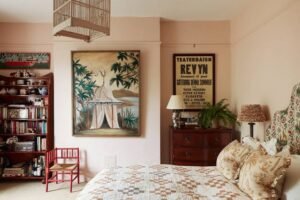 Cozy guest bedroom featuring floral bedding, vintage wooden furniture, framed artwork, bookshelves, and warm neutral tones for a welcoming and comfortable retreat.
