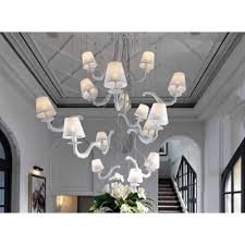 Elegant white chandelier with multiple fabric lampshades suspended from a decorative ceiling, adding classic sophistication to a bright, luxurious interior.
