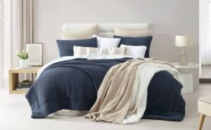 Modern bed styled with layered bedding, decorative pillows, and a soft throw blanket draped across the foot of the bed.