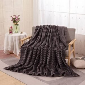 Chunky knitted throw blanket draped over a modern armchair in a bright, cozy living space.
