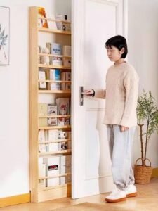 Slim pull-out storage shelf installed behind a bedroom door, holding books, small household items, and decorative accessories to maximize narrow unused spaces.