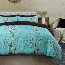 Light turquoise floral bed sheet set with delicate cherry blossom branch patterns and matching pillowcases in a contemporary bedroom.